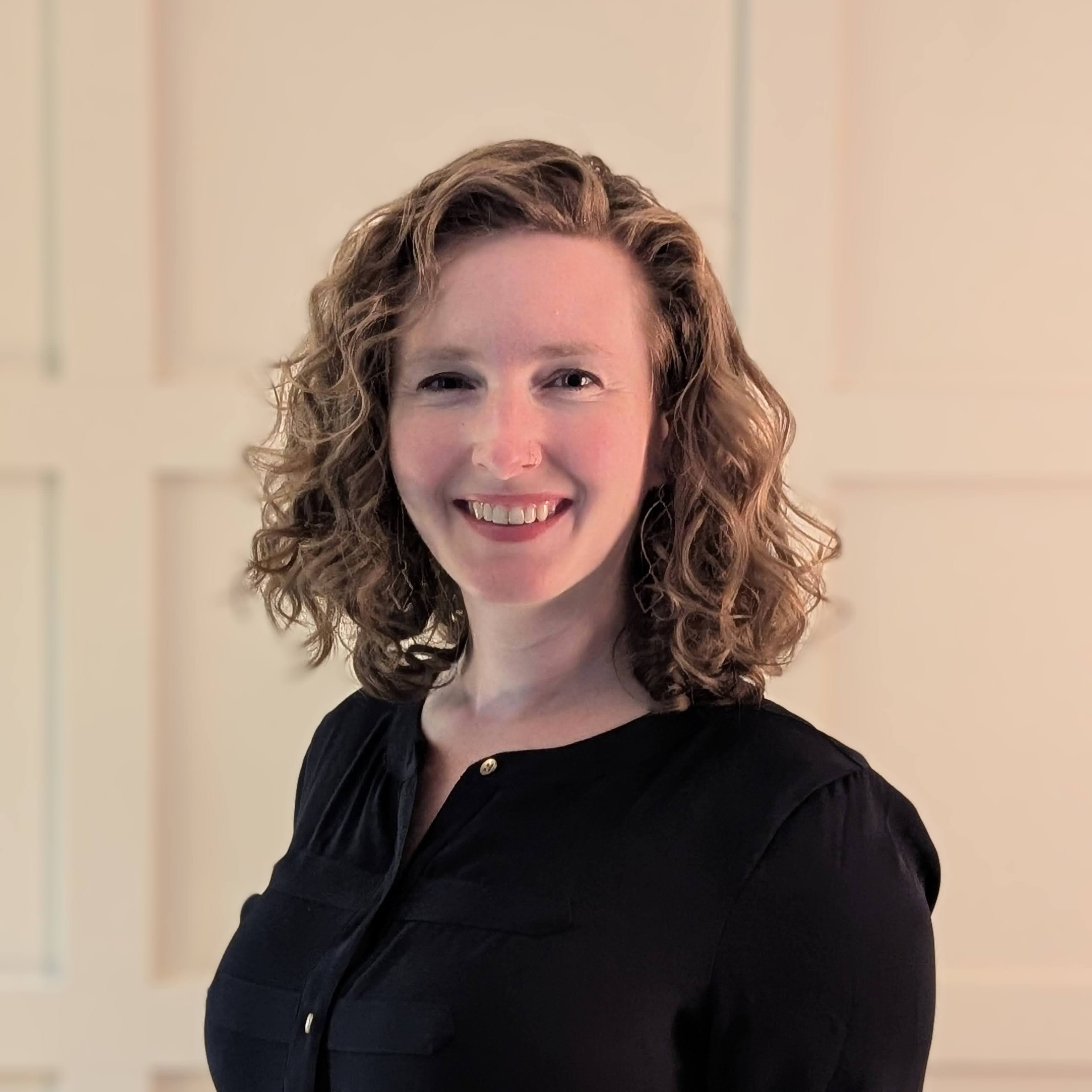 Liz, smiling in a portrait against a paneled wall